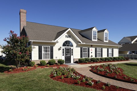the front of a white house with a landscaped front yard