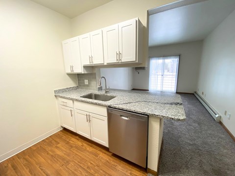 A kitchen with white cabinets and a granite countertop.