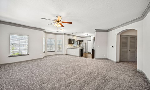A spacious room with a ceiling fan and carpeted floor.