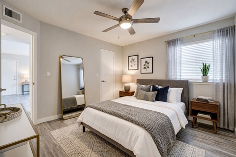 A bedroom with a large bed, a ceiling fan, and a mirror.