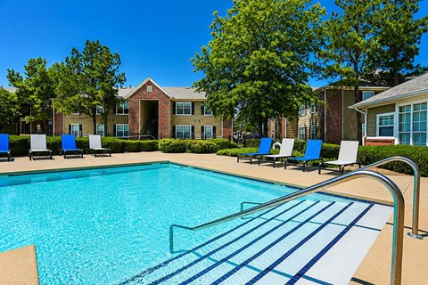 A swimming pool with a metal railing and blue water in front of a building with a red brick wall.