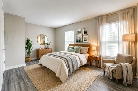 A bedroom with a large bed, a chair, and a plant.