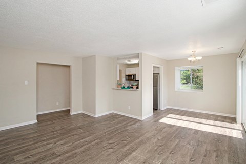 A spacious room with wood flooring and a large window.