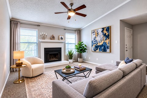 A living room with a grey couch, a fireplace, and a painting on the wall.