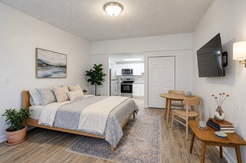 A bedroom with a bed, a table, and a television.