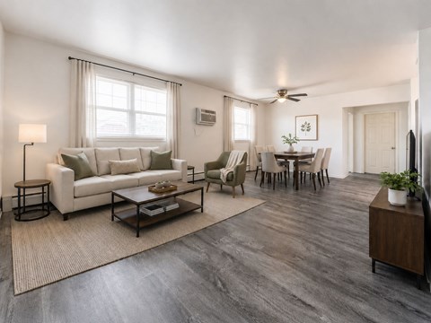 A living room with a white couch, a coffee table, and a dining table with chairs.