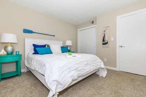 a bedroom with a white bed and blue pillows    and a door