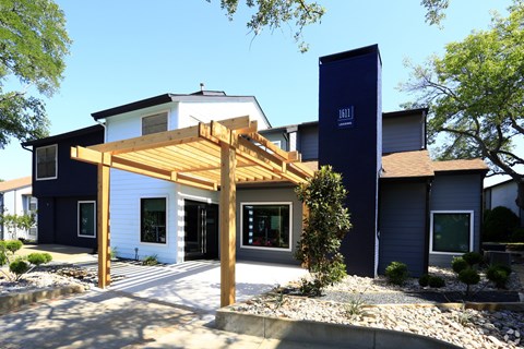 A modern house with a white and blue exterior and a wooden pergola.