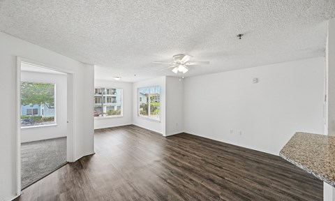 A spacious room with wood flooring and a ceiling fan.