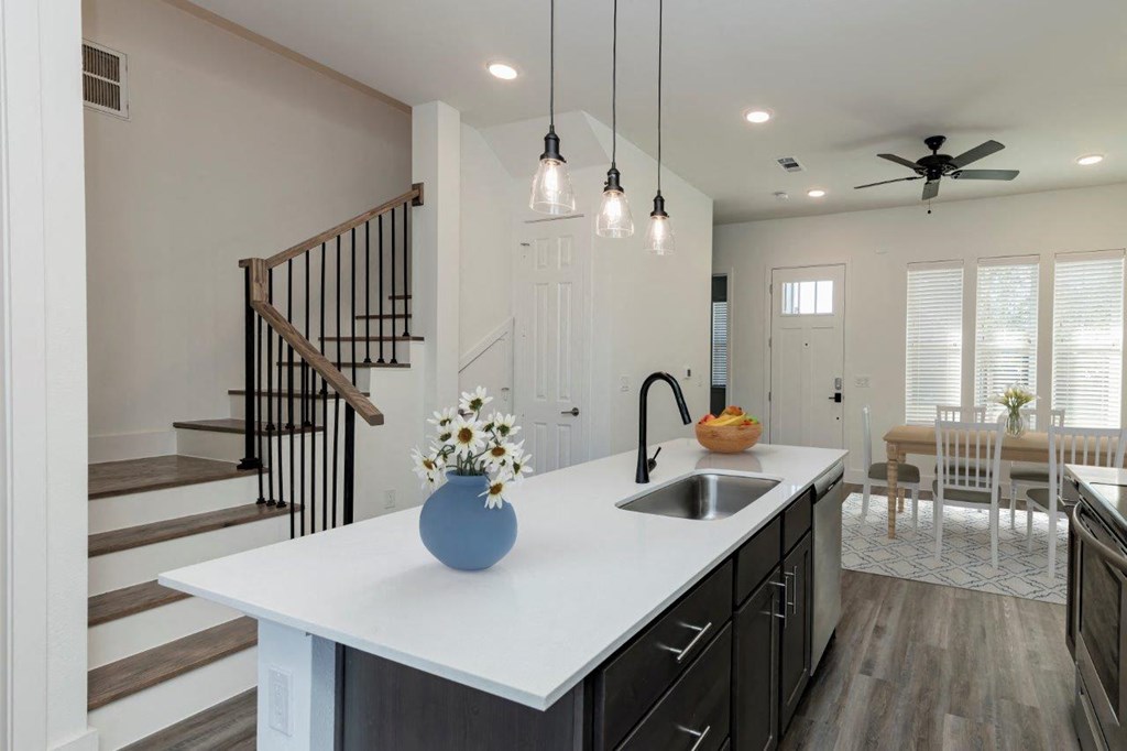 a white kitchen with a sink and a staircase