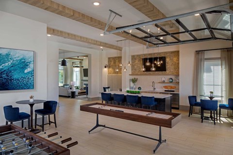 A modern dining room with a foosball table and blue chairs.