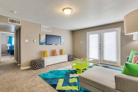 A living room with a grey couch and a green rug.