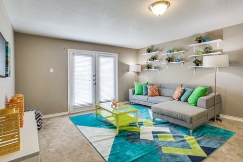 A living room with a grey couch, a yellow coffee table, and a blue rug.