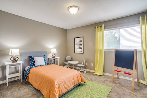 A bedroom with a bed, nightstands, and a chair.