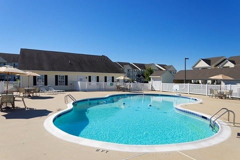 A large outdoor swimming pool with a white fence surrounding it.