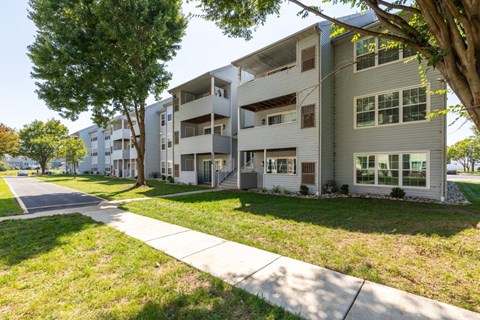 Apartment building with a sidewalk and trees in front.