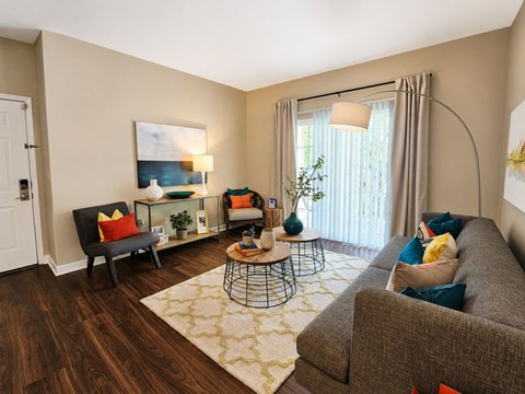 A living room with a grey couch, a black chair, a coffee table, and a painting on the wall.