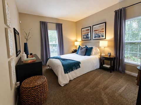 A bedroom with a large bed and a wicker stool.