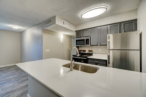 A kitchen with a white counter top and stainless steel appliances.