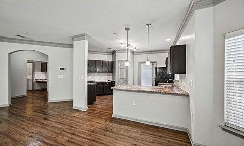 A kitchen with a black fridge and a wooden floor.