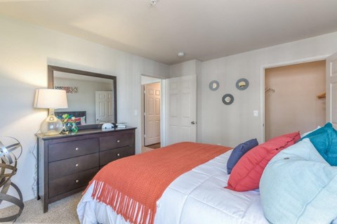 A bedroom with a bed, dresser, and mirror.