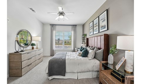 A bedroom with a large bed, a dresser, and a ceiling fan.