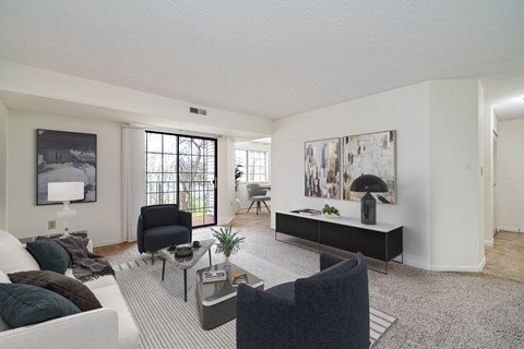 A living room with a white couch, a black chair, and a grey coffee table.