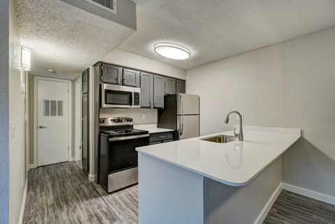 A kitchen with a white counter top and stainless steel appliances.