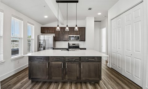A modern kitchen with dark brown cabinets and white countertops.