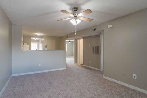 A spacious room with a ceiling fan and carpeted floor.