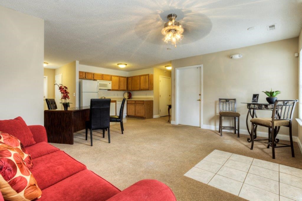 a living room and kitchen with a red couch and a table