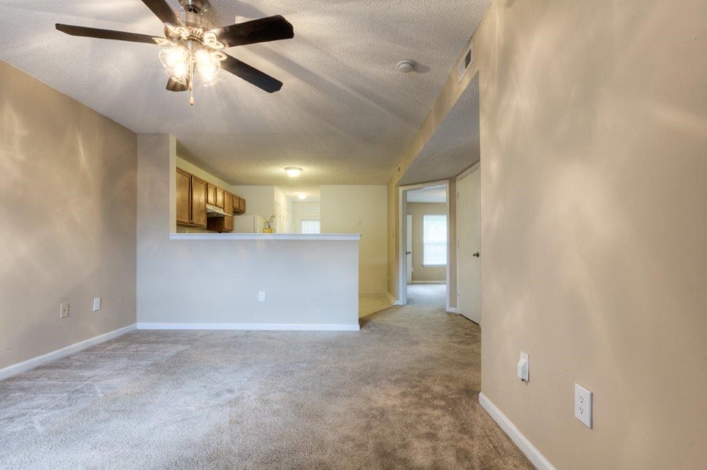 a empty living room and kitchen with a ceiling fan