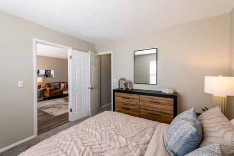 A bedroom with a large bed, a dresser with a mirror, and a lamp.