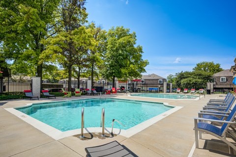 A large swimming pool surrounded by trees and lounge chairs.