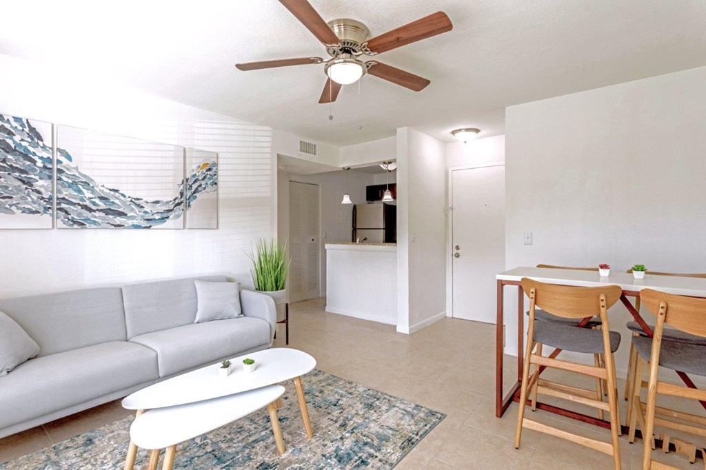 A living room with a grey couch, a white coffee table, and a ceiling fan.
