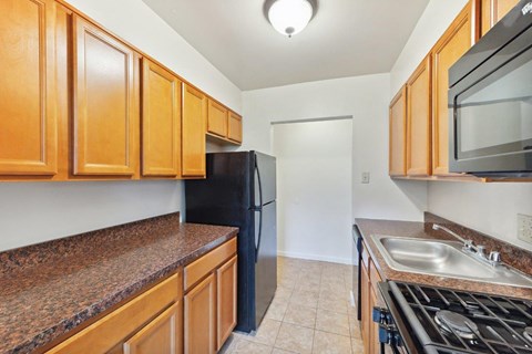 A kitchen with brown cabinets and black appliances.