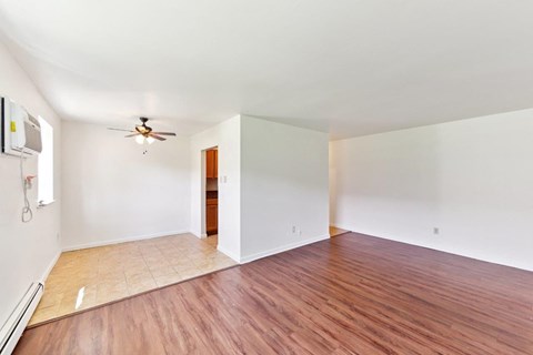 an empty living room with wood floors and a ceiling fan