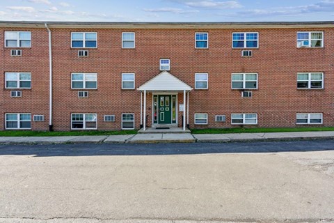 the front of a brick building with a green door