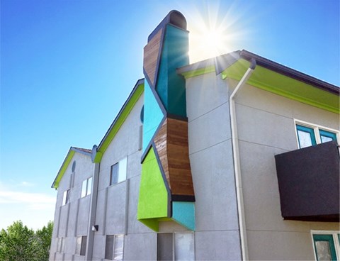 A modern building with a green and brown design is basking in the sunlight.