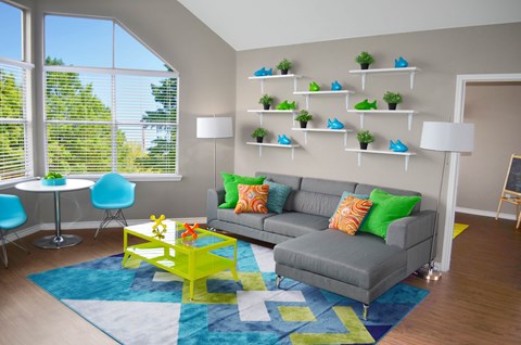 A living room with a grey couch, a yellow coffee table, and a blue rug.