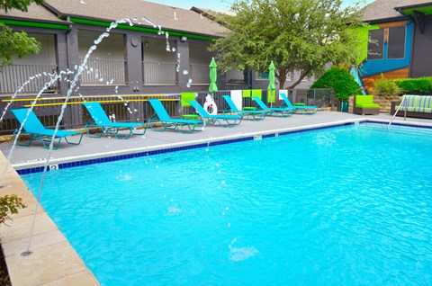 A pool with a waterfall and lounge chairs.