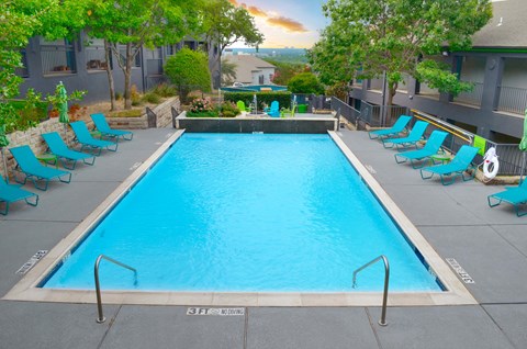 A swimming pool surrounded by blue lounge chairs.