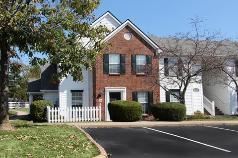 A white house with a red brick chimney and black shutters.