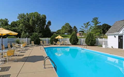 A large blue swimming pool surrounded by yellow chairs and umbrellas.