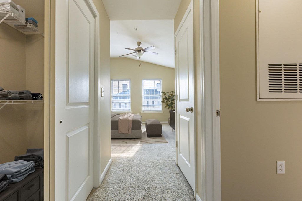 a bedroom with a closet and a living room with a ceiling fan