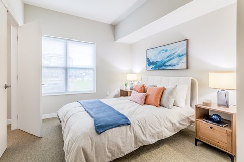 A bedroom with a large bed and a painting on the wall.