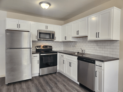 A kitchen with white cabinets and a black countertop.