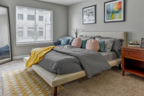 A bedroom with a bed, a nightstand, and two framed pictures on the wall.