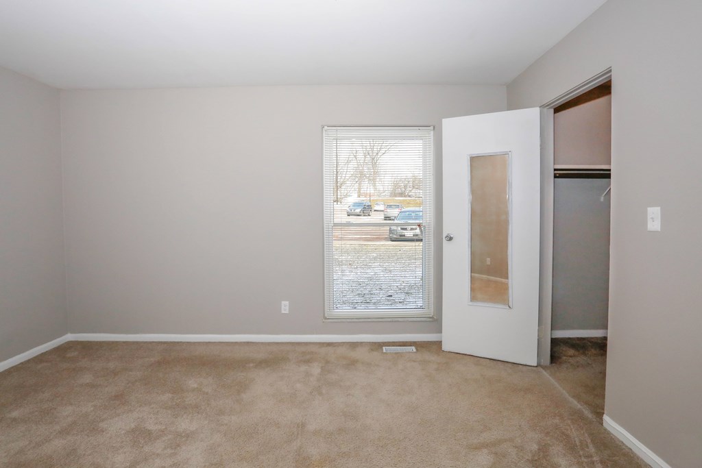 A room with a carpeted floor and a door leading to a parking lot.