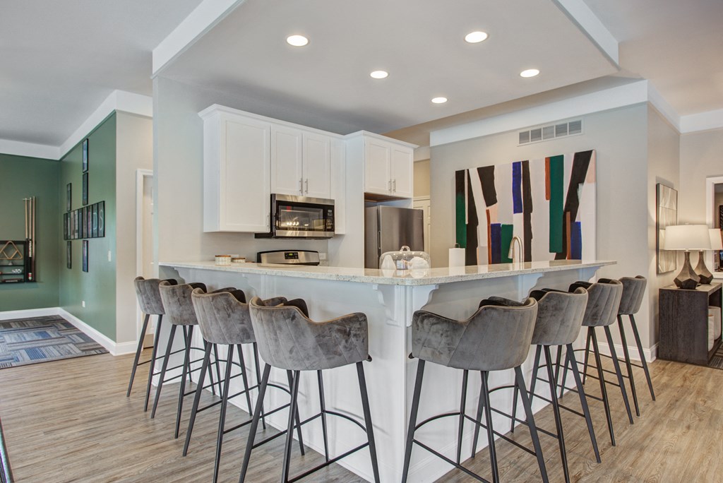 a kitchen with bar stools and a counter with chairs